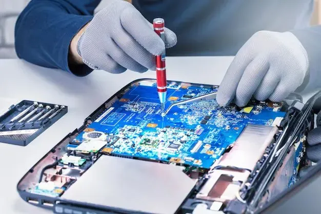 Técnico con guantes reparando la tarjeta de una laptop